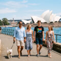 family walking a dog with sydney opera house in the background