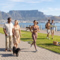 happy retired mixed race couple walking their shihzu in cape town on the promenade